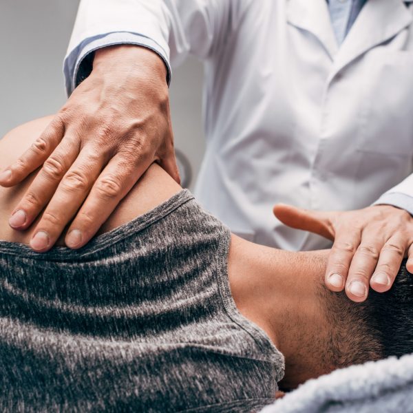 chiropractor in white coat massaging neck of man